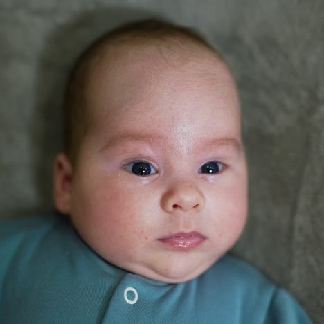 little baby watching intensely into the camera. cute child on the grey background. close up