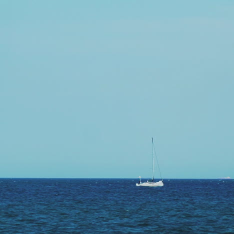 the yacht is under sail floats in the sea. on the horizon are seen cargo ships