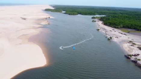 kitesurfer riding in a brazilian delta between sand and jungle