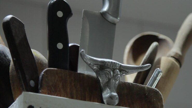 Pan right of knife block with menacing arrangement of knives and metal bull head