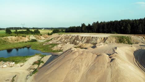 drone pan shot of dunes and pits in a quarry , showing contrast between nature and industry