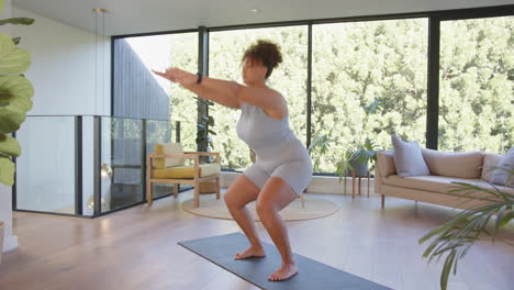 exercising on yoga mat, plus size woman doing squats in modern living room