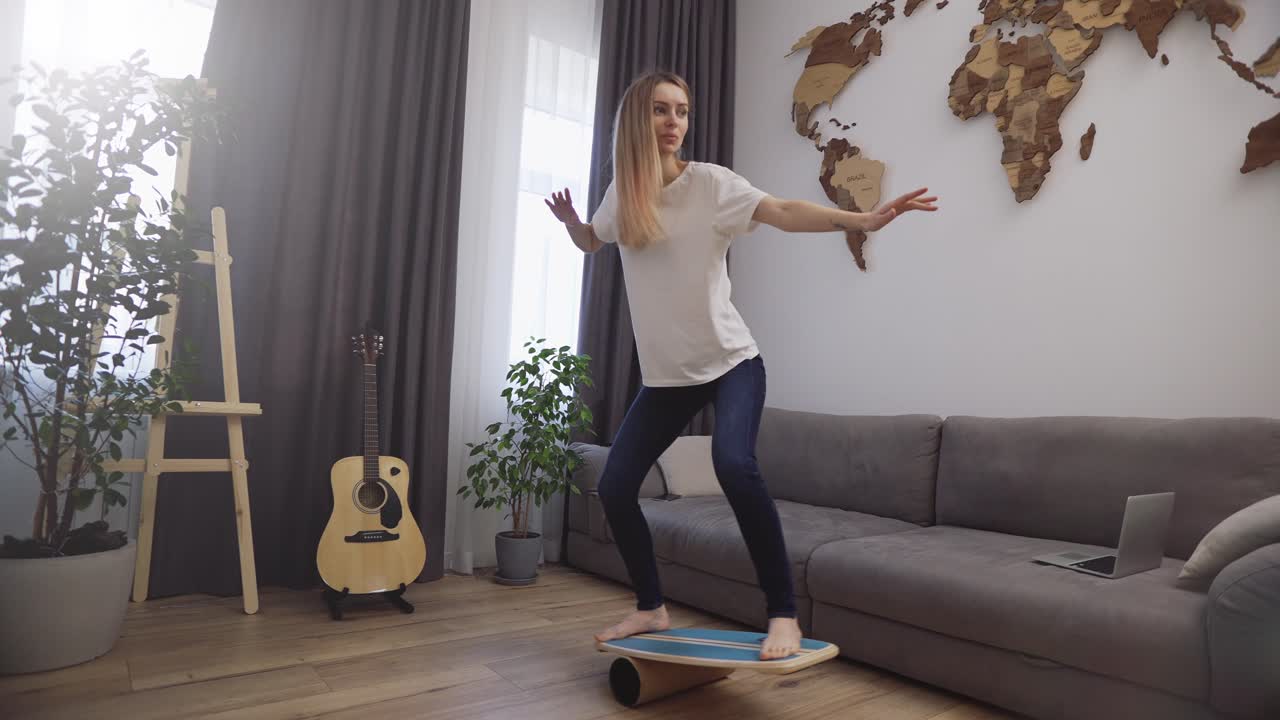 mujer divertida en la cubierta para el equilibrio se para con sus pies, fingiendo que está surfeando