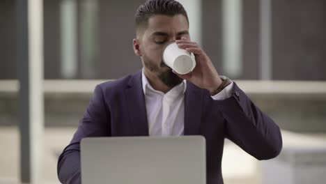 hombre serio trabajando con computadora portátil al aire libre