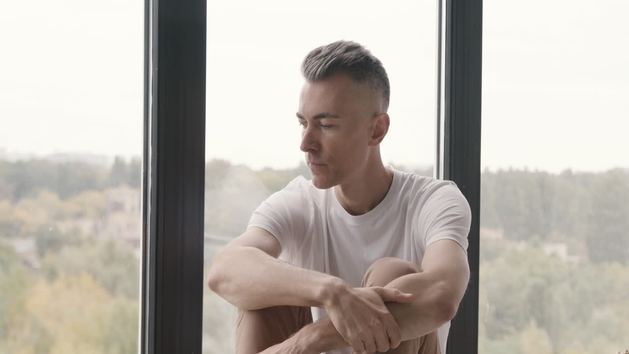 Suffering Middle Aged Man Sitting At Window Worrying About Something While Woman Putting Blanket On His Shoulder And Taking Care Of Him