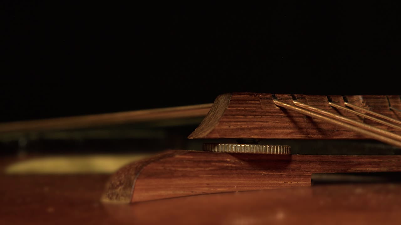 La luce si diffonde sul ponte e sulle corde di un vecchio mandolino impolverato nell'oscurità.