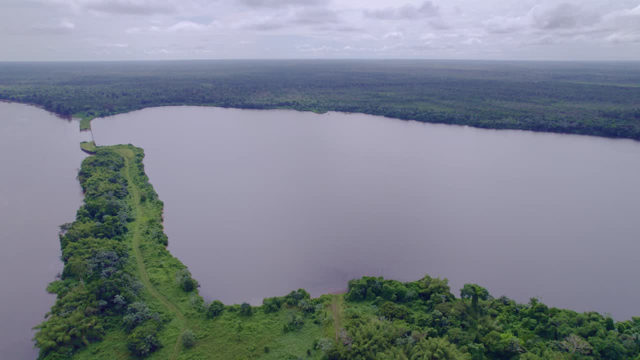 Fly past lake with road meeting river in the Amazon, South America