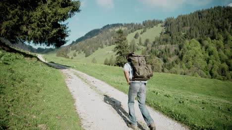 backpacker millennial man hiking on rural countryside dirt path, slow motion