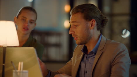 man showing woman something on computer in office