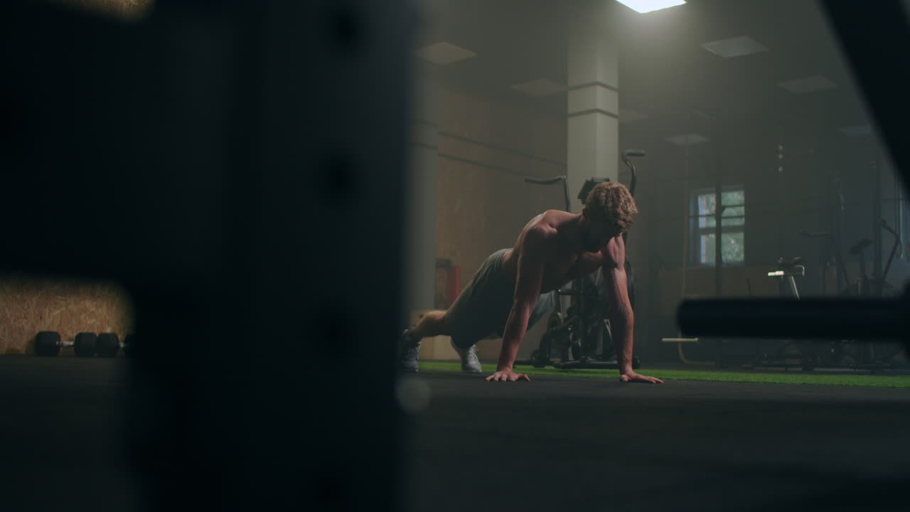 a strong man performs push-UPS from the floor with all his strength. a pumped-up man does push-UPS in the gym