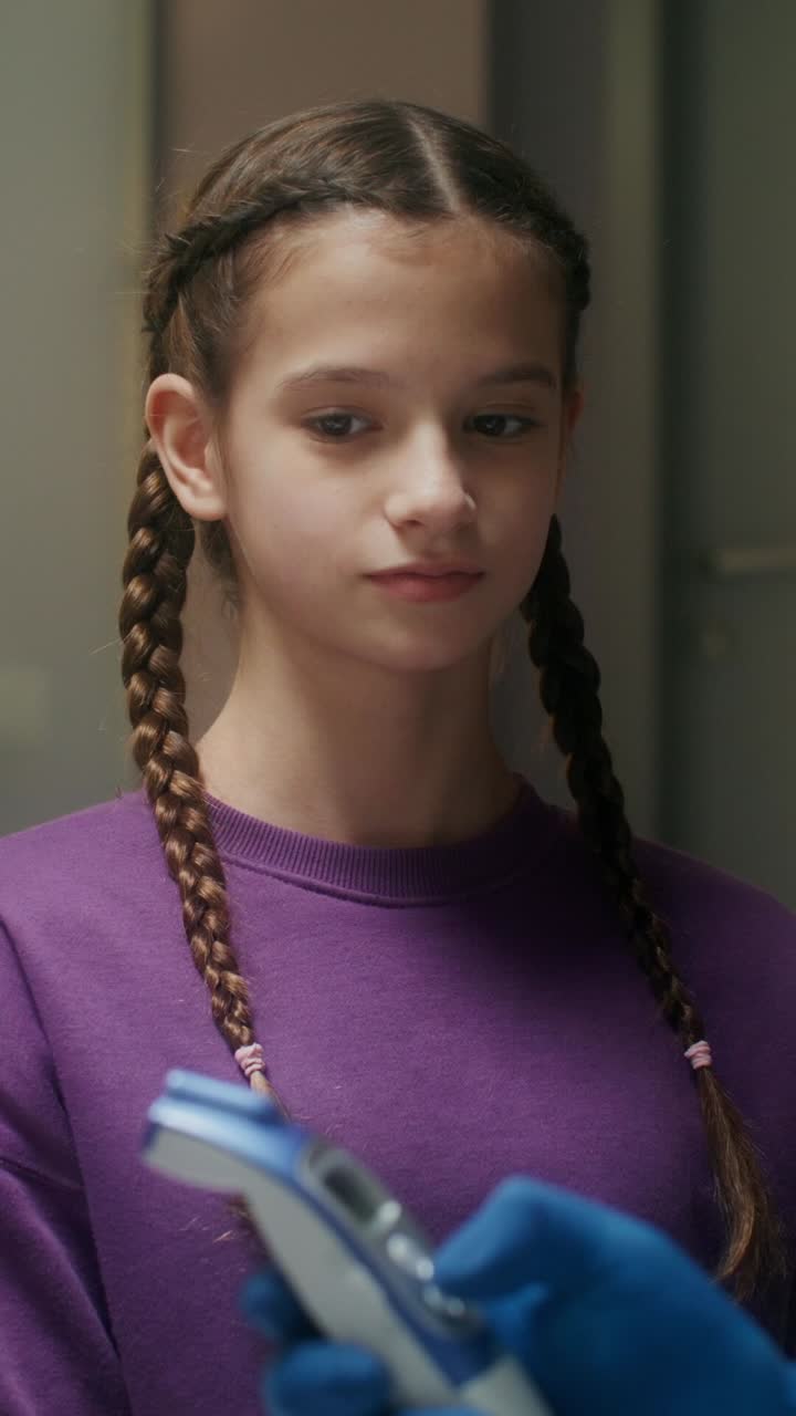 una niña que tiene la temperatura comprobada por un médico