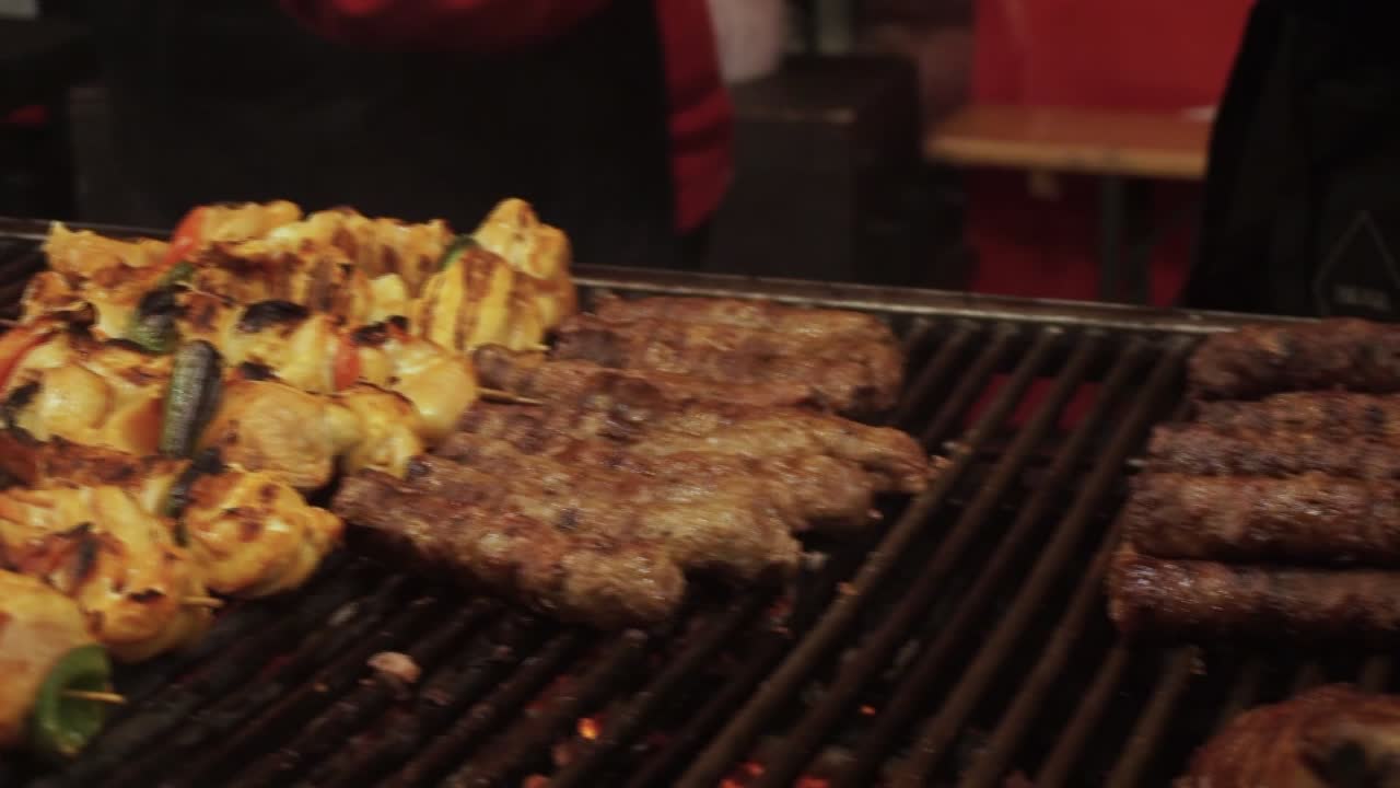 Carne di pecora naturale e biologica che cuoce su una griglia a legna e carbone all'aperto a un tradizionale festival della carne, primo piano dello chef che preleva la carne dalla griglia