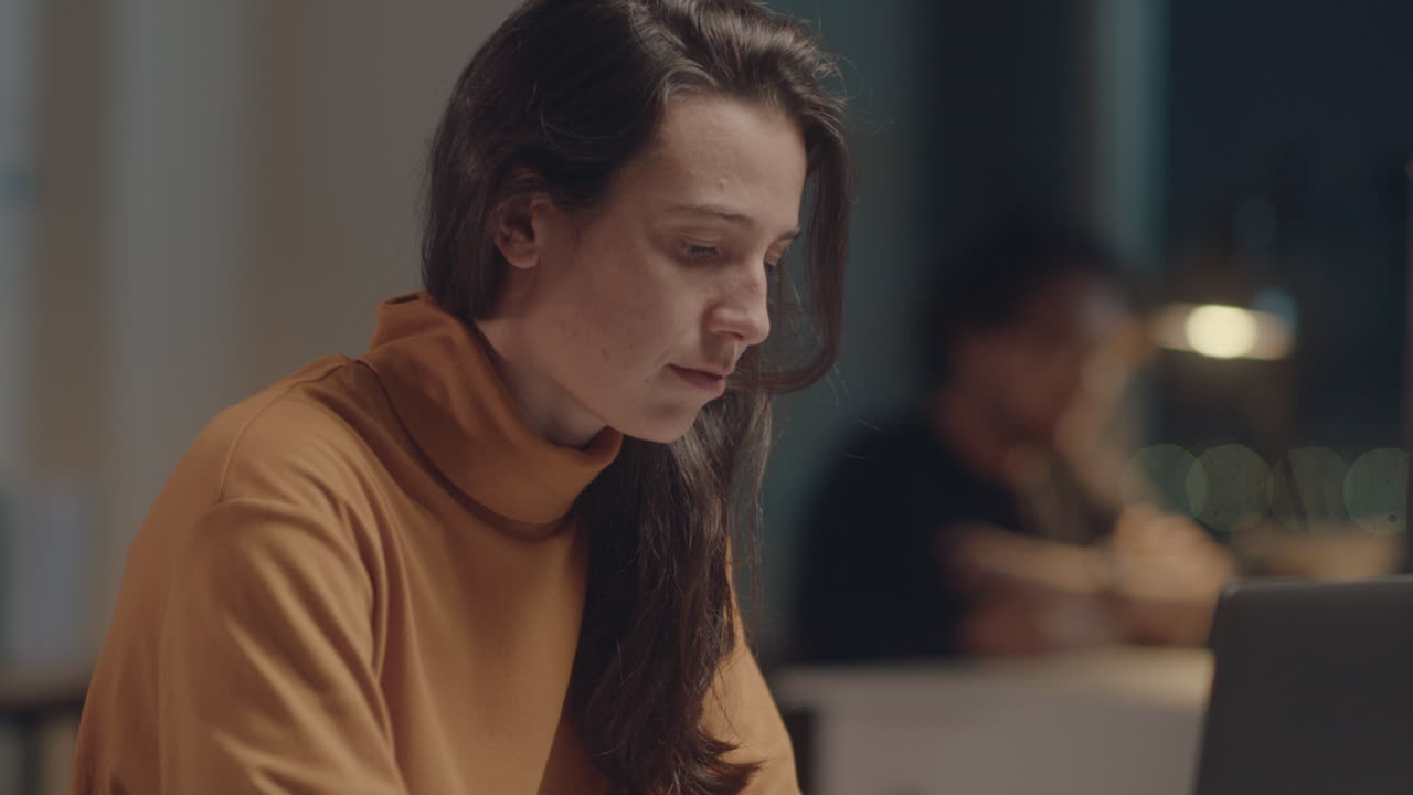 Young Woman Using Laptop in Office at Night
