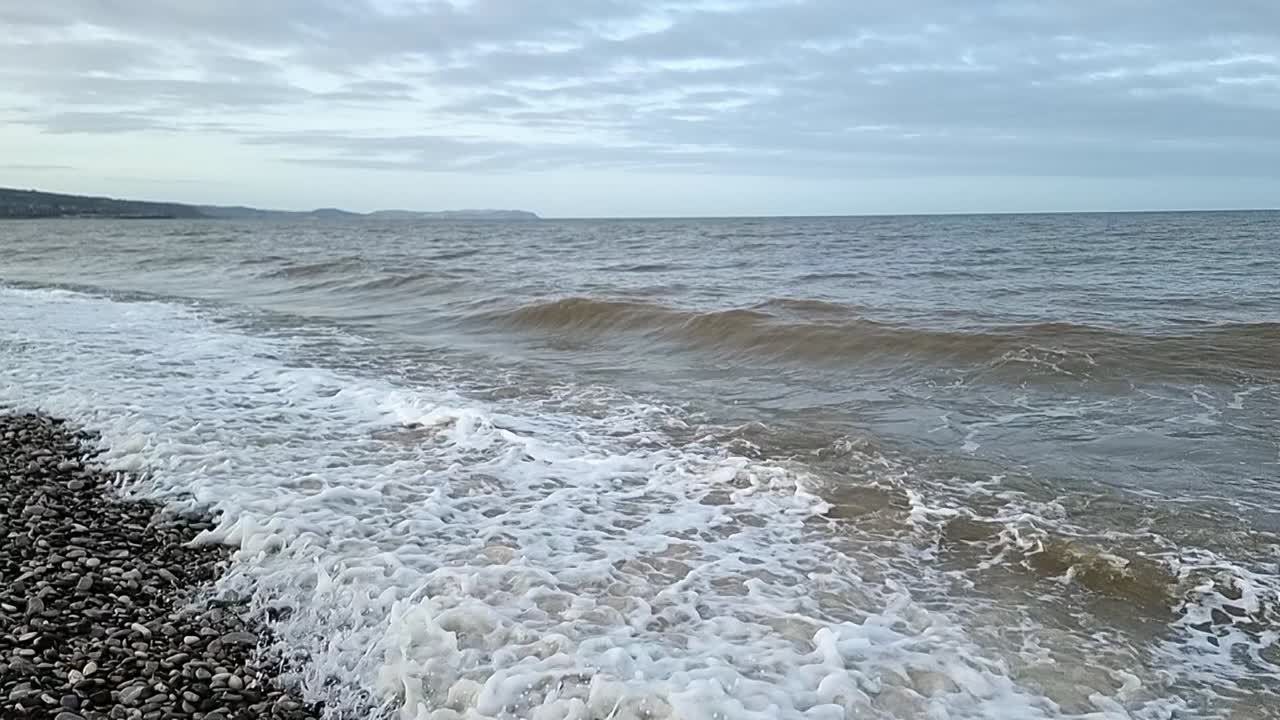 모래 물결이 슬로우 모션으로 이란두노의 자갈 해변에 부히고