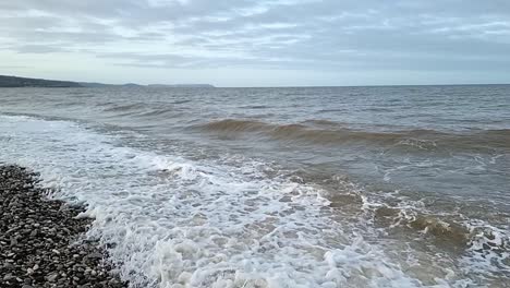 Sandige-Wellen-Stürzen-In-Zeitlupe-Auf-Den-Kiesstrand-Von-Llandudno