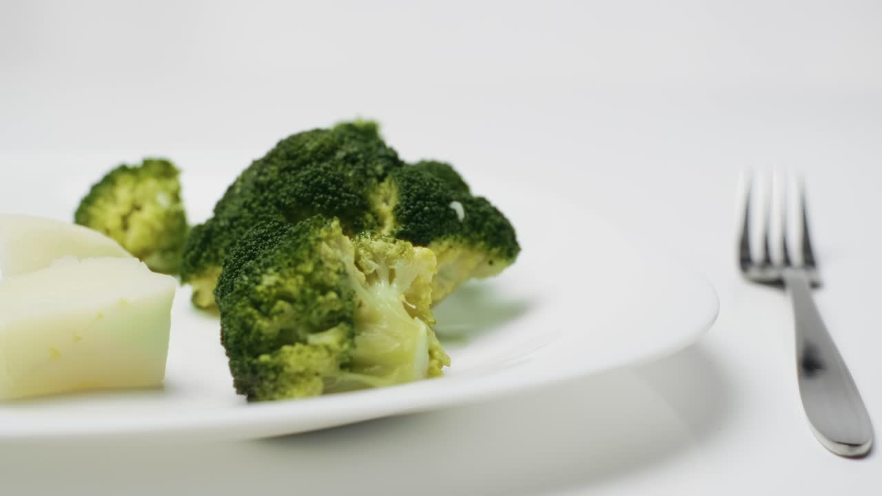 Dolly in motion of Fresh cooked broccoli and potato on white plate, Close-up shot