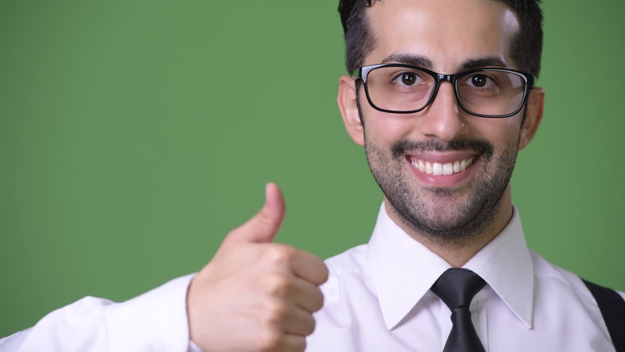 joven empresario persa barbudo y guapo contra un fondo verde