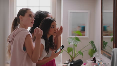 happy teenage girls taking photos in bathroom posing making faces enjoying hanging out together having fun sharing sleep over on social media