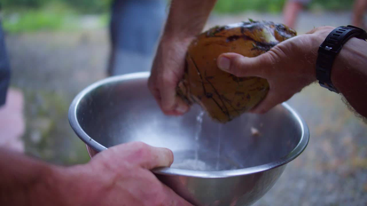 agua de coco fresca vertida en un tazón al aire libre en costa rica después de abrir el coco