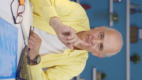 Vertical-video-of-Home-office-worker-old-man-looking-at-camera-with-a-stern-angry-warning.