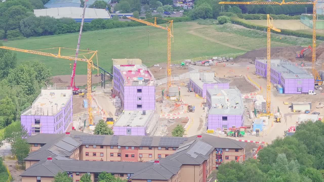 Aerial close up of major residential development under active construction near Stoke, England, showing large site, machinery, and surrounding greenery, suburban out-of-city area, daytime