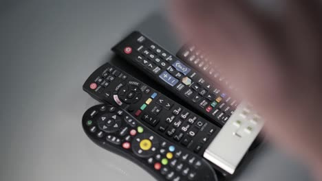 mans hands pushing remote controls off coffee table in frustration