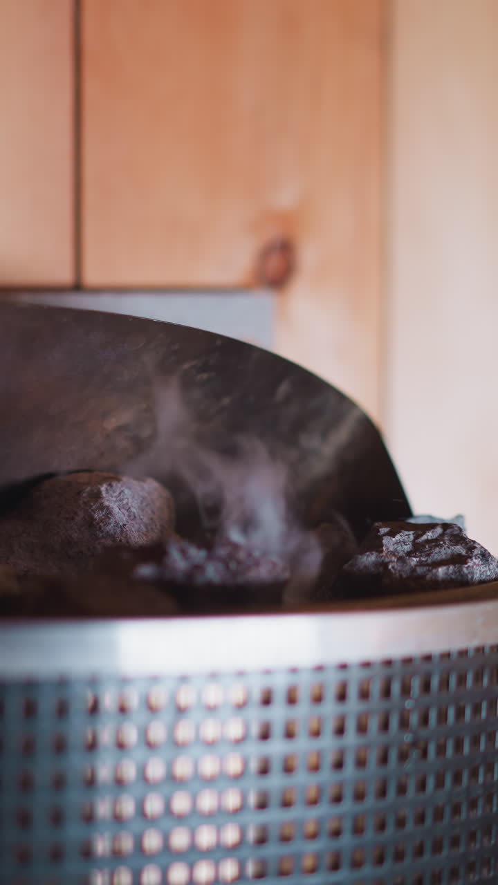 Dripping essential oil onto hot rocks in sauna closeup. Creating relaxing atmosphere and improving positive health impact in hammam. Air refreshing