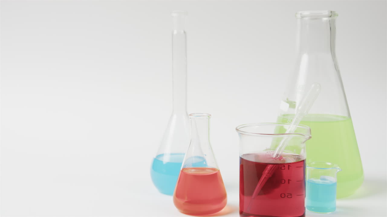 líquidos de color en frascos sobre fondo blanco con espacio para copiar, cámara lenta