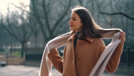 young woman adjusting her scarf and coat outdoors
