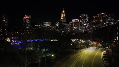 illuminated custom house tower and boston skyscrapers at night. twinkling blue and white lights decorate rose kennedy greenway. vibrant city aerial with historic charm.