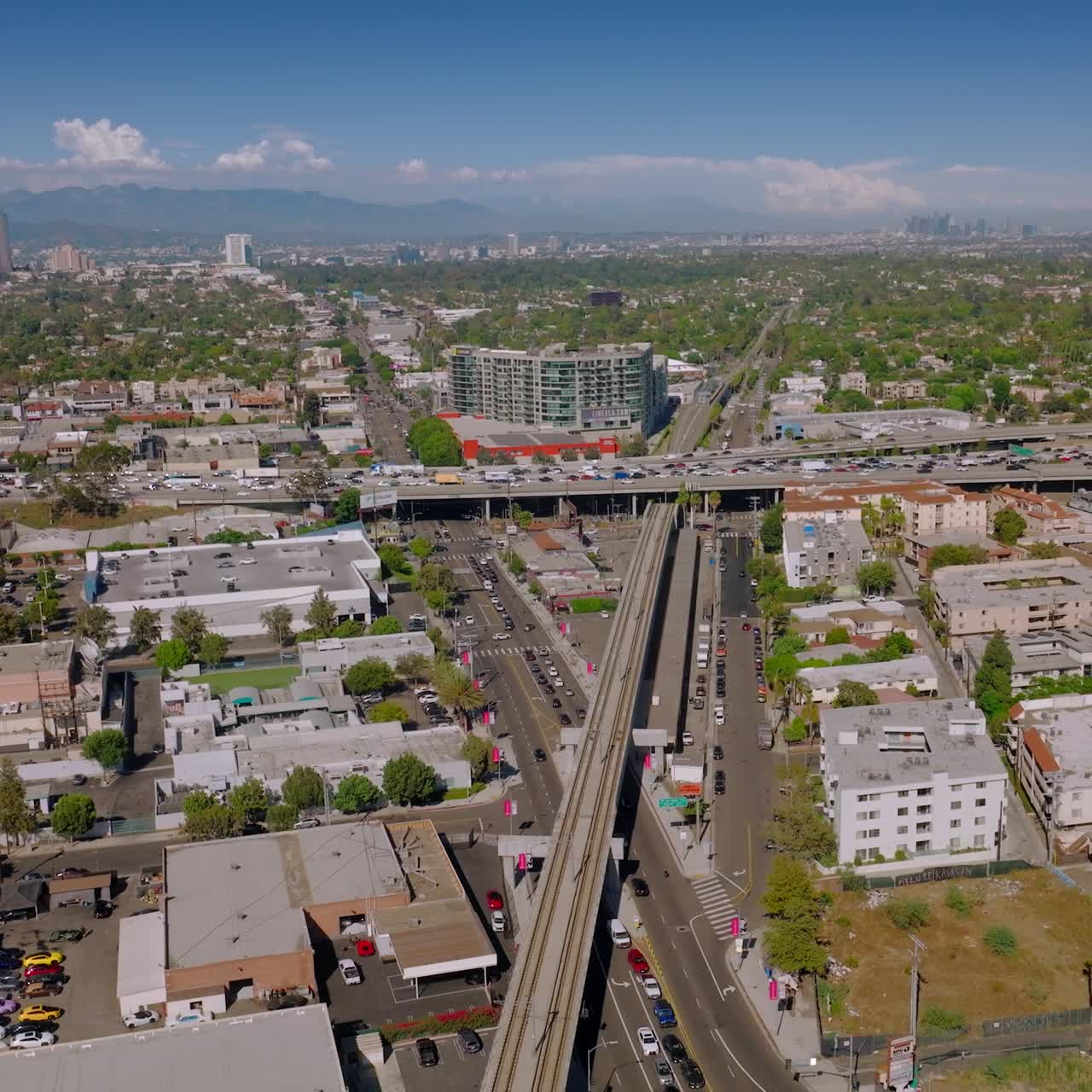 Low buildings in urban district of Los Angeles, California. Busy roads crossing the city with multiple cars moving quickly. Sunny day footage. Top view