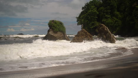 powerful waves crashing into rocks along a tropical shore spraying and splashing white foam into the sky - slow motion