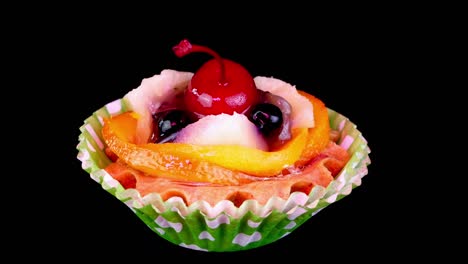 pastel de crema con cereza, bayas, frutas sobre fondo negro girar lentamente.