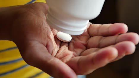 person taking pills from a bottle