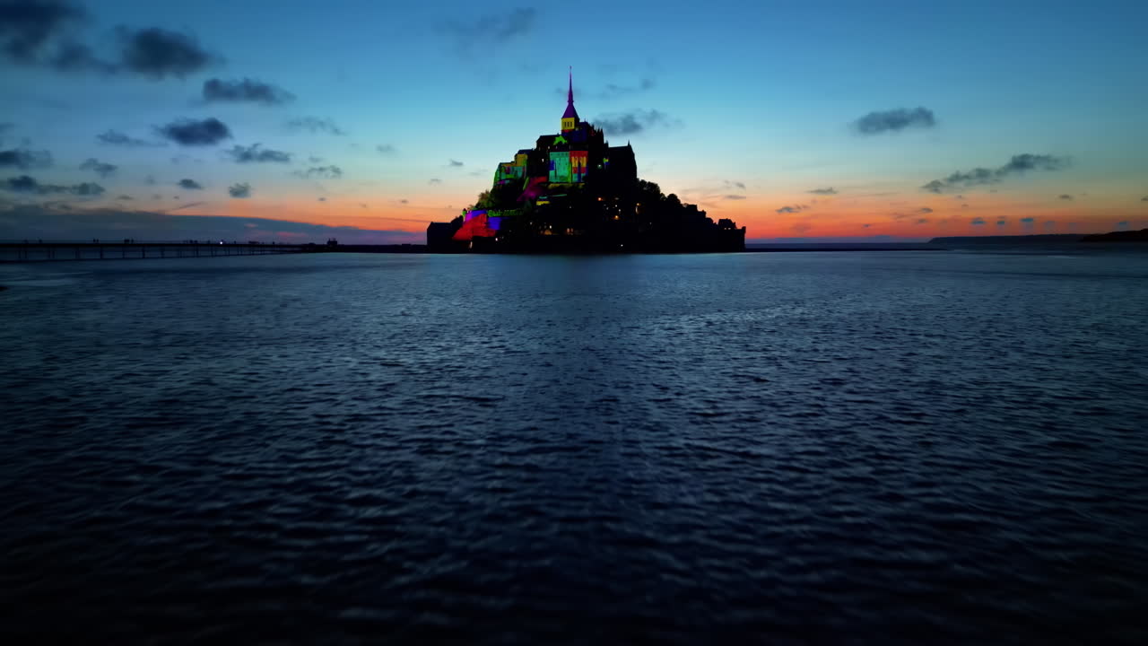 Aerial drone view of Mont-Saint-Michel at sunset in Normandy, France. Illumination in the town, water of the English Channel