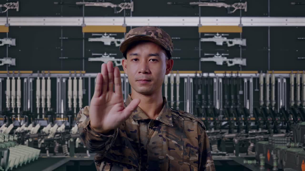 Seorang tentara pria Asia melihat ke kamera dan menunjukkan ketidaksetujuan tanpa isyarat tangan di Gudang Senjata Militer