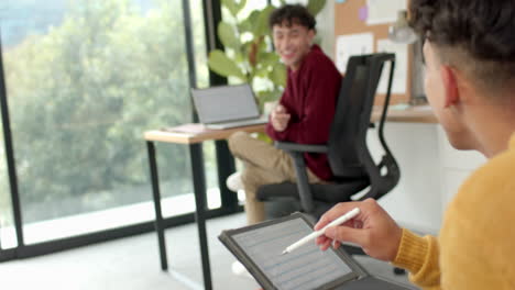 Using digital tablet with stylus, man working while partner in background, at home
