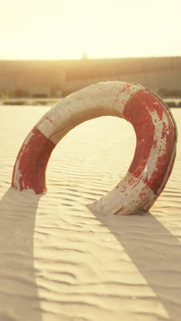 old life preserver on sandy beach at sunset