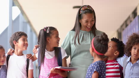 teacher smiling with group of diverse students holding books at school