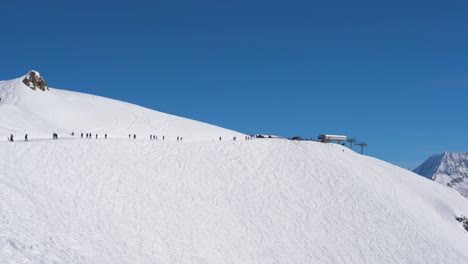 sunny day in the mountains at a ski resort many skiers on the slope