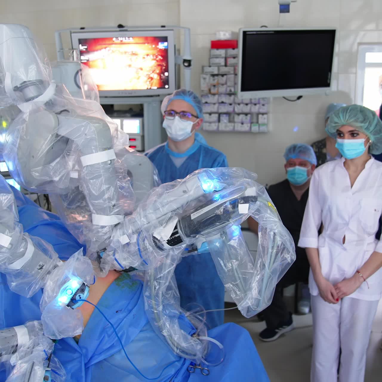 Clinic staff gathered in a surgery room to see the work of advanced futuristic equipment. Da Vinci robot operates the patient on a surgery table