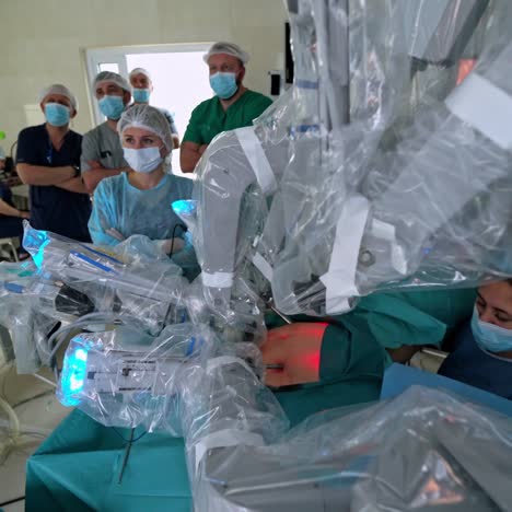 robotic system on a patient during surgery. doctors in masks control the removal surgery via minimally invasive robotic surgery. hi-tech medical robot in futuristic operation room.