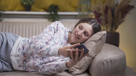 Young-woman-lying-on-sofa-is-using-phone.-Pleasant-and-comfortable-posture.