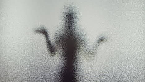 a female silhouette behind the frosted window dances slowly