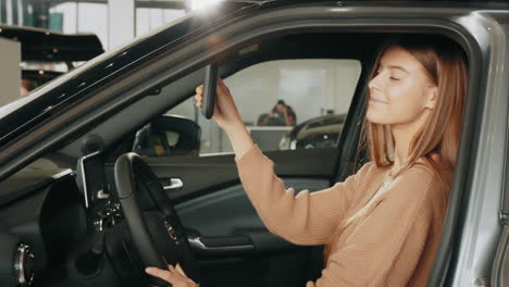 mujer ajustando el espejo del coche en la sala de exposiciones