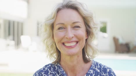 Portrait-of-smiling-caucasian-woman-looking-at-camera-by-pool