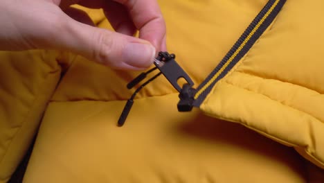 the girl's hands remove the price tag from the yellow jacket with scissors.