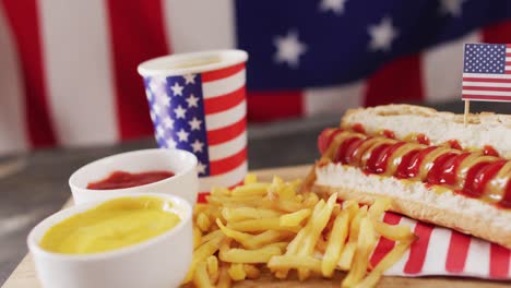 Video-of-hot-dogs-with-mustard,-ketchup-and-chips-over-flag-of-usa-on-a-wooden-surface
