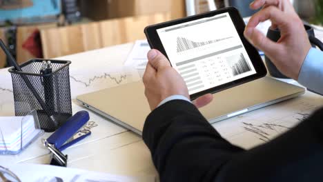 male hands of young businessman developing a business project and analyzing statistical data information on a tablet pc. successful entrepreneur working on modern digital device in office. close up