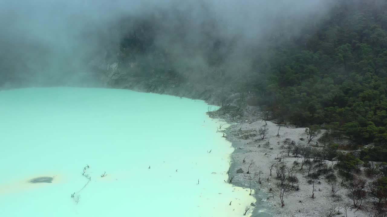 aerial landscape of Kawah Putih with foggy clouds on neon green sulfur lake
